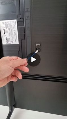 a hand is pointing at the bottom of a refrigerator with its door open and label on it