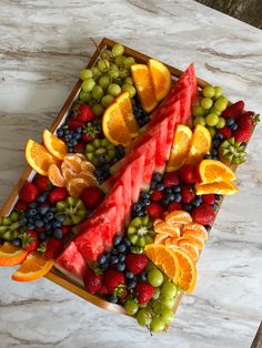 a platter filled with watermelon, oranges, grapes and strawberries