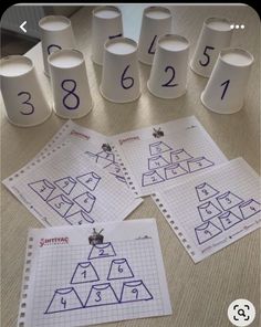 four sheets of paper with numbers on them sitting on a table next to some cups