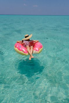 a person floating on an inflatable raft in the ocean with a hat on their head