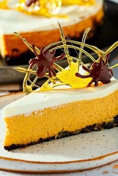 a piece of cheesecake on a plate with chocolate decorations and gold leaf decoration around the edges