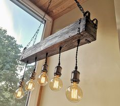 three light bulbs hanging from a wooden beam in front of a window with chains on it