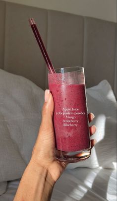 a hand holding a glass with a drink in it and two straws sticking out of the top