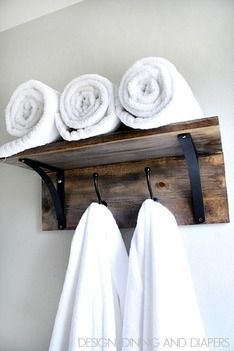 four white towels are hanging on a wooden shelf