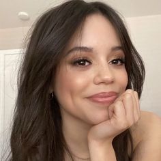 a close up of a person with long dark hair and brown eyes wearing a necklace