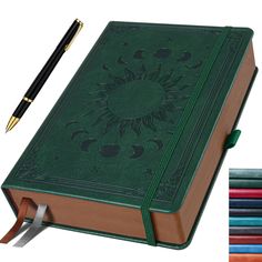 a green book with a pen on top and several colored pencils next to it