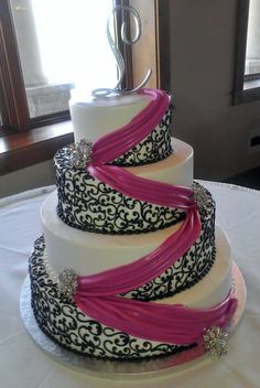 a three tiered wedding cake with pink ribbons