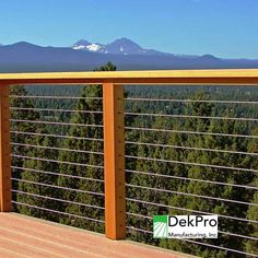 a wooden deck with metal railings and mountains in the background