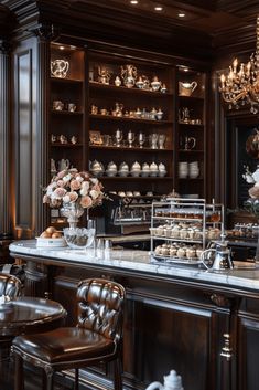 an elegantly decorated bar with chandeliers and vases filled with flowers on the counter