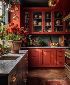 a kitchen with red cabinets and flowers in vases on the counter top next to an oven