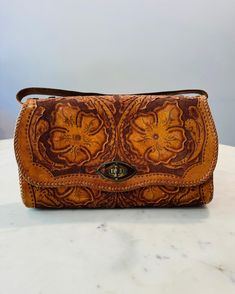 1970's beautiful floral hand-tooled leather handbag with a wrist strap that can be worn as a clutch purse. The interior is made of dark brown leather with three separate zipper pockets. The Interior is slightly worn, with one zipper chain missing, but still functions properly with no stains or tears. The Exterior is in great condition, a stunning purse! Purse measures around 11 x 6. Ladies Purses Handbags, Vintage Handheld Clutch For Everyday Use, Vintage Satchel Clutch For Everyday Use, Vintage Crossbody Clutch For Daily Use, Handheld Brown Leather Wallet, Vintage Handheld Clutch For Daily Use, Vintage Everyday Crossbody Clutch, Vintage Leather Clutch For Everyday Use, Hand-tooled Handheld Brown Shoulder Bag