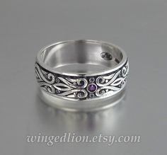 a silver ring with an amethorate stone in the center and filigrees on it