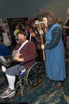 a man in a wheel chair being pushed by a woman dressed as mary poppies