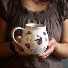 a woman holding a coffee mug with snails on it