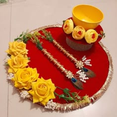 a table topped with yellow roses and cupcakes on top of a red tray