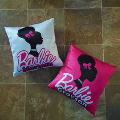 two decorative pillows on the floor with pink and white pillow cases that say barbie crayon