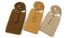 three crocheted bags with tassels are lined up on a white surface