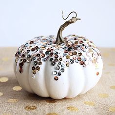 a white pumpkin with lots of sequins on it's top sitting on a table