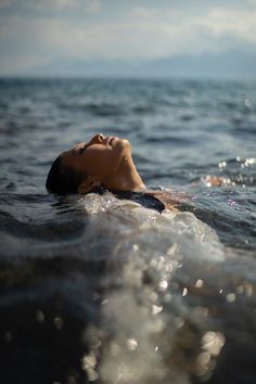 a woman is floating in the ocean with her head above the water's surface