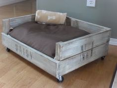 a bed made out of old wooden crates with wheels on each side and a pillow in the middle