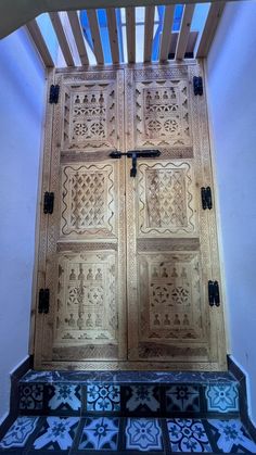 an intricately carved wooden door with blue and white tiles on the steps leading up to it