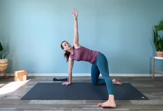 a woman is doing yoga on a mat in the middle of a room with blue walls