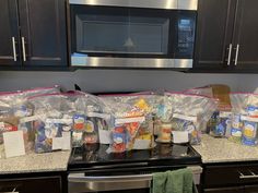 the kitchen counter is covered with plastic bags and food in front of the stove top