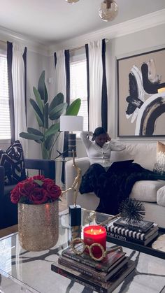 a living room with a couch, coffee table and vase filled with flowers on top of it