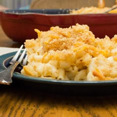 a close up of a plate of food on a table with a fork and bowl in the background