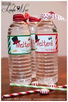 two bottled water bottles sitting on top of a wooden table next to candy canes