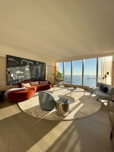 a living room filled with furniture and large windows overlooking the ocean on a sunny day