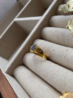 an open box with three rings in it on top of some cloth covered cases,