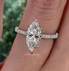 a woman's engagement ring with a pear shaped diamond in the center and side stones on