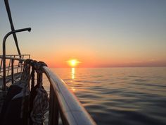 the sun is setting over the ocean as seen from a boat