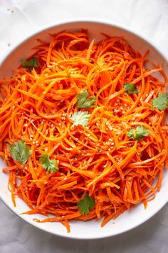 a white bowl filled with shredded carrots and cilantro