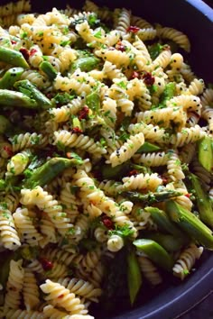 a blue bowl filled with pasta and asparagus