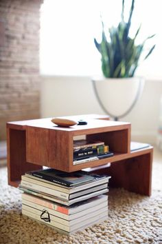 a coffee table with books stacked on it and a potted plant in the background