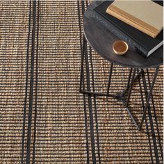 a table with a book on top of it next to a rug that has black and tan stripes