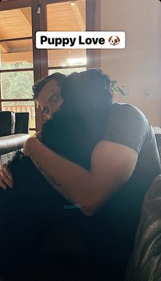 a man hugging a woman on top of a couch in front of a window with the caption puppy love