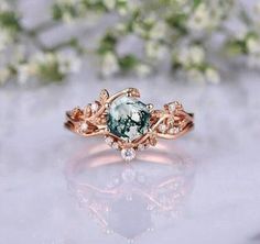 an engagement ring with a green stone surrounded by white flowers