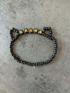 a black beaded bracelet with the word karma written in gold letters on top of it