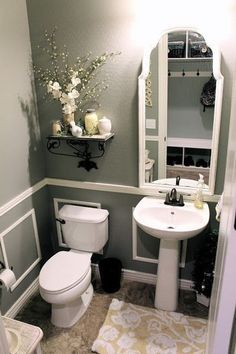 a white toilet sitting next to a sink in a bathroom under a mirror with flowers on it