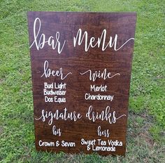 a wooden sign sitting on top of a grass covered field next to a lush green field