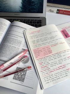 an open book sitting on top of a desk next to a laptop computer and pen