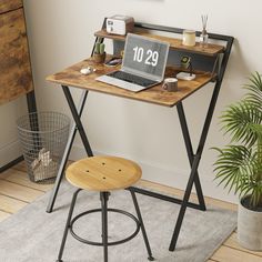 a laptop computer sitting on top of a wooden desk next to a potted plant