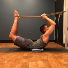 a man is doing an exercise on a mat with a resistance band in his hands