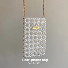 the pearl phone bag is hanging from a gold chain