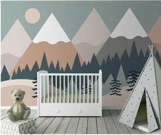 a baby's room with mountains painted on the wall and a white crib