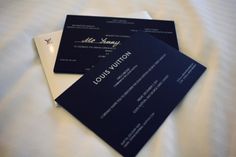 two black and white business cards sitting on top of a bed