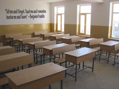 an empty classroom with wooden desks and windows